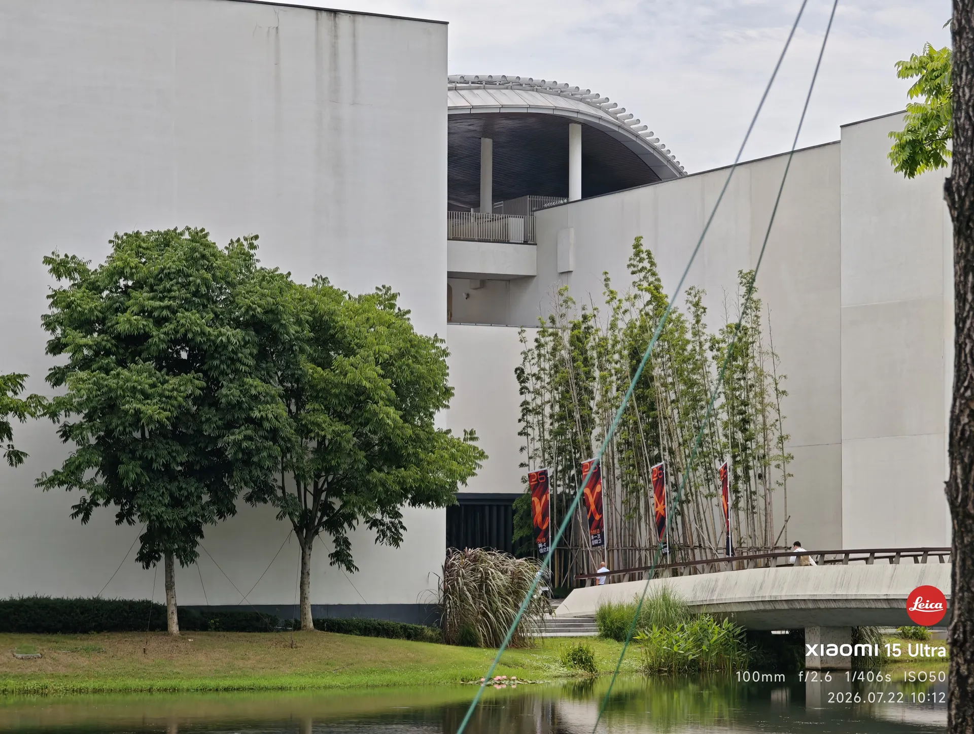 隔着水面望向湖畔创研中心的白色建筑群,岸边插着 AdventureX 的旗帜