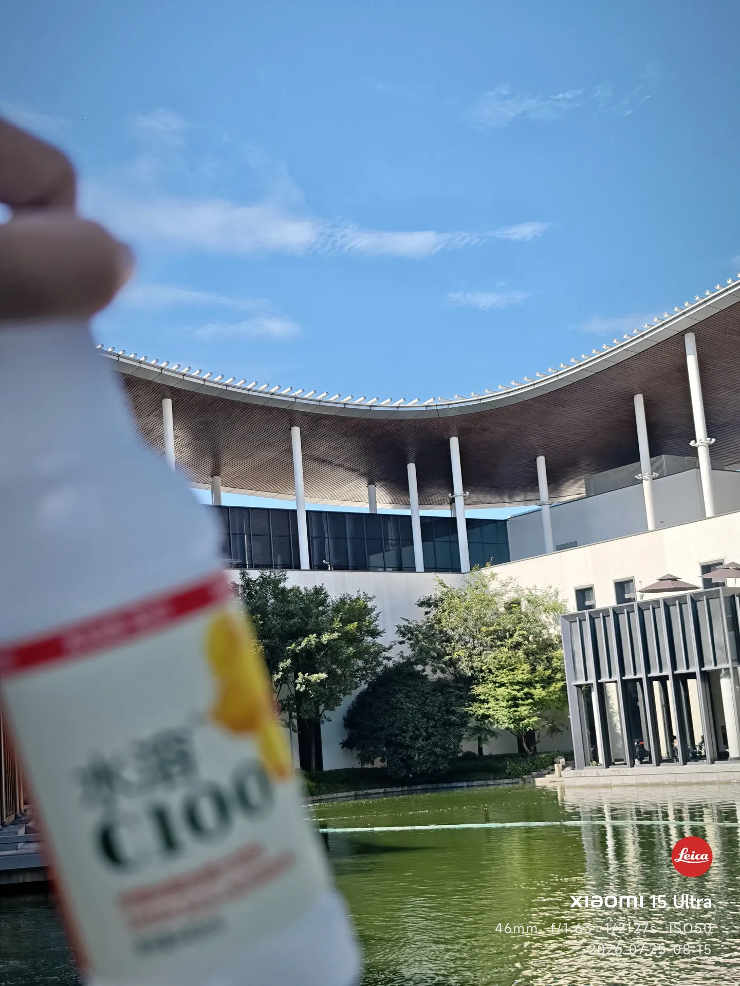 熬夜后的清晨,桌上摆着一瓶外星人电解质水,背后是湖畔的弧形屋顶和蓝天